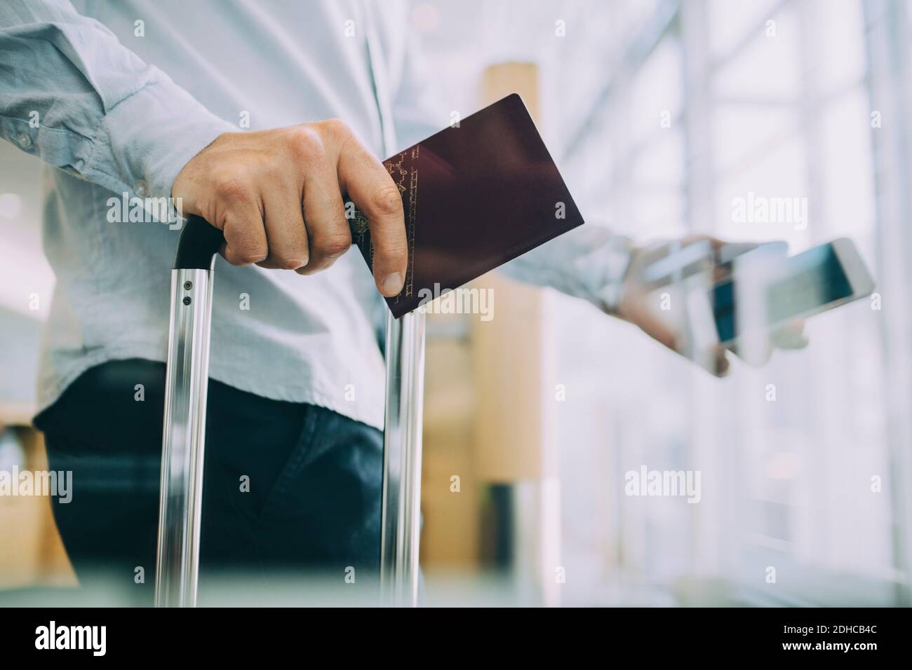 Midsection of businessman holding passport at airport Stock Photo