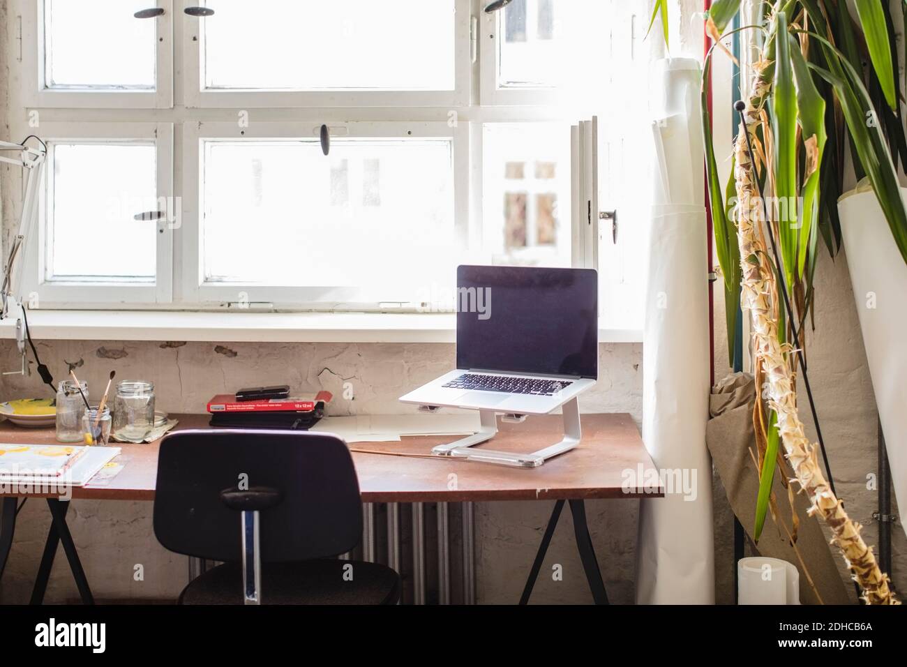 Laptop on stand at desk against window in office Stock Photo