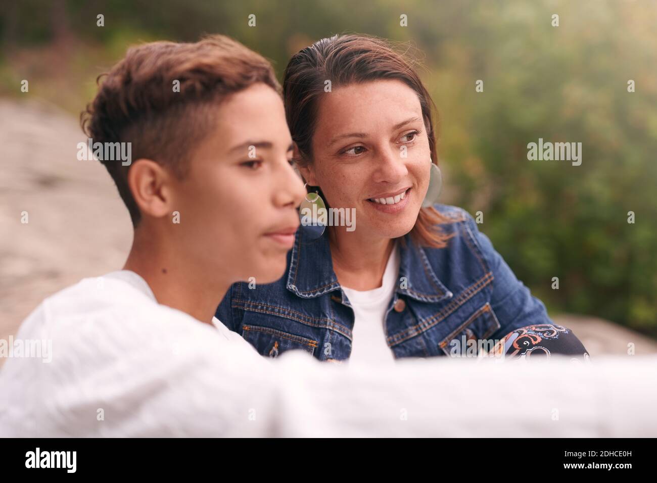 Mother and son looking away while sitting in park Stock Photo
