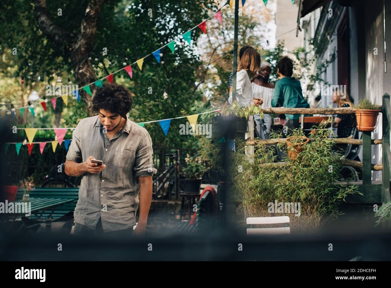 Young man using mobile phone while standing in backyard Stock Photo