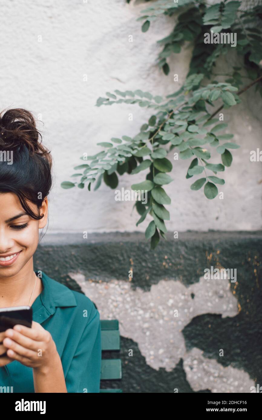 Cropped image of young woman using mobile phone against wall Stock Photo