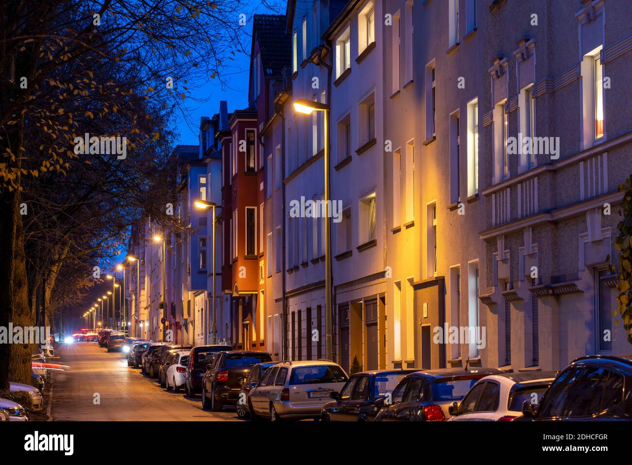 Wohnstrasse, viele Mehrfamilienhäuser in einem Wohnviertel, abends, Laternen Beleuchtung, Essen, NRW, Deutschland Stock Photo