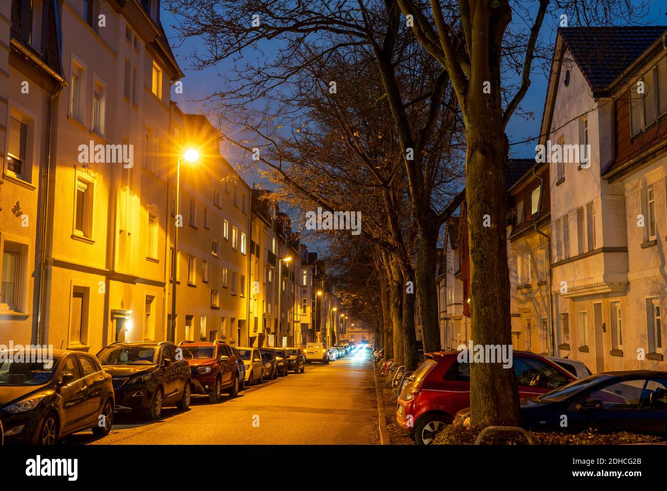 Wohnstrasse, viele Mehrfamilienhäuser in einem Wohnviertel, abends, Laternen Beleuchtung, Essen, NRW, Deutschland Stock Photo