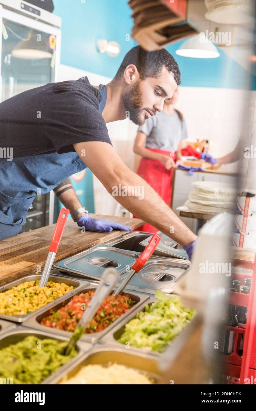 Confident young salesman preparing food at restaurant Stock Photo