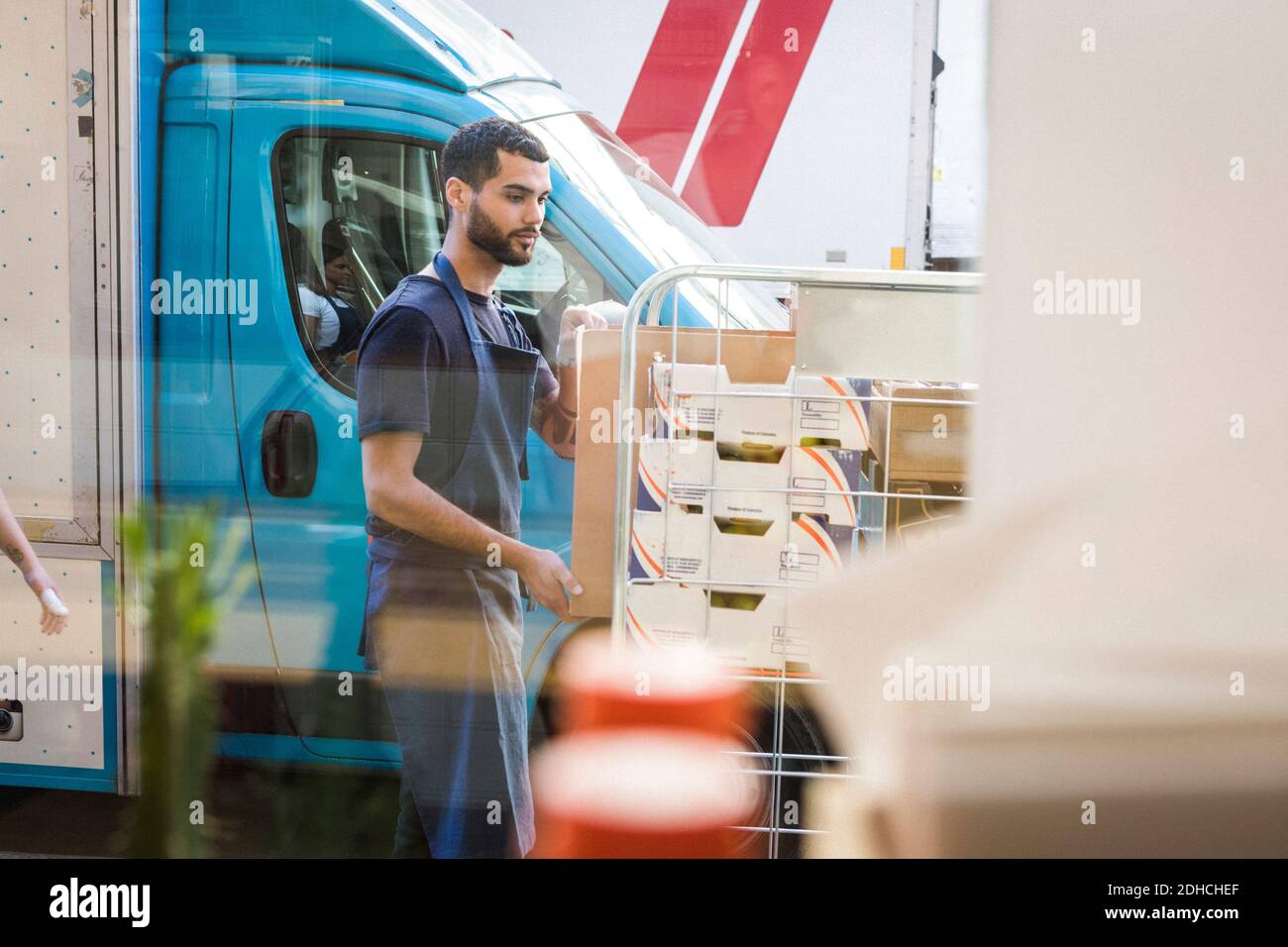 Young male owner standing by rack against food truck seen through ...