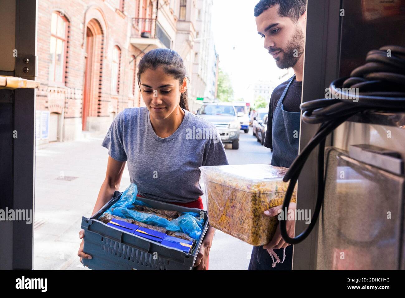 Young multi-ethnic owners carrying food at truck in city Stock Photo