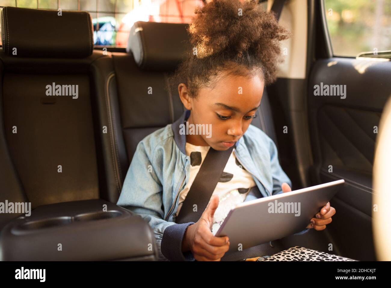 Girl using digital tablet while sitting in electric car Stock Photo
