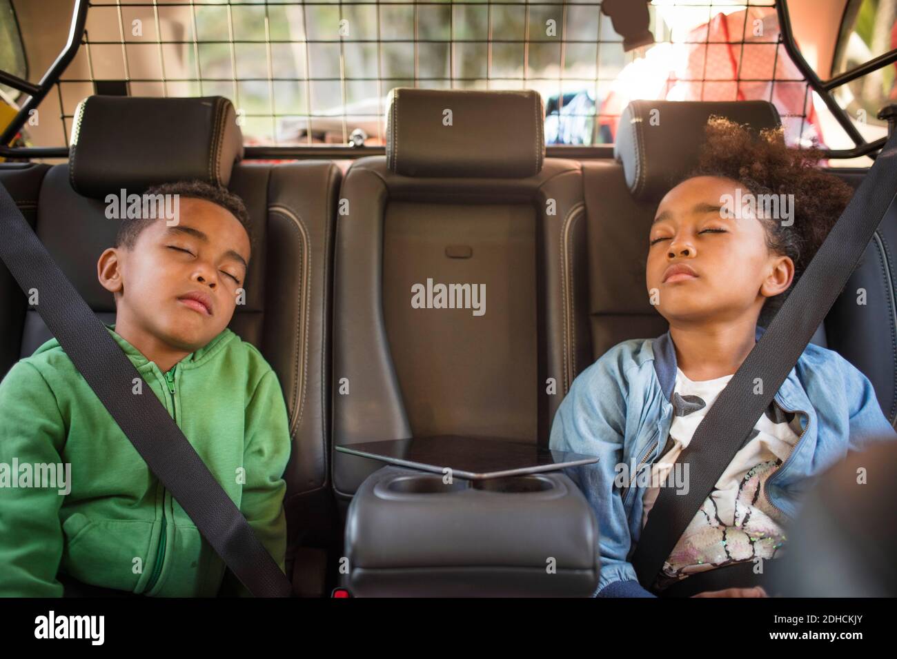 Tired siblings sleeping in electric car Stock Photo