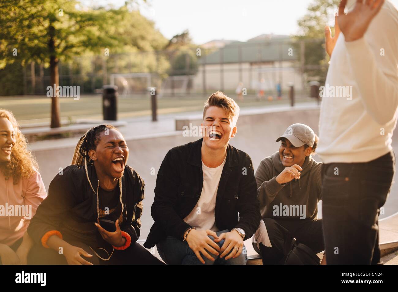 Cheerful multi-ethnic friends talking at skateboard park Stock Photo