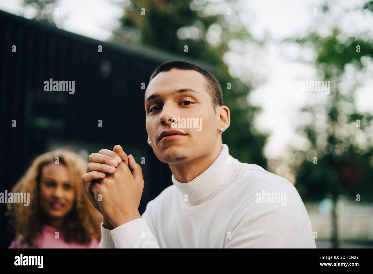 Portrait of young man with woman in background Stock Photo