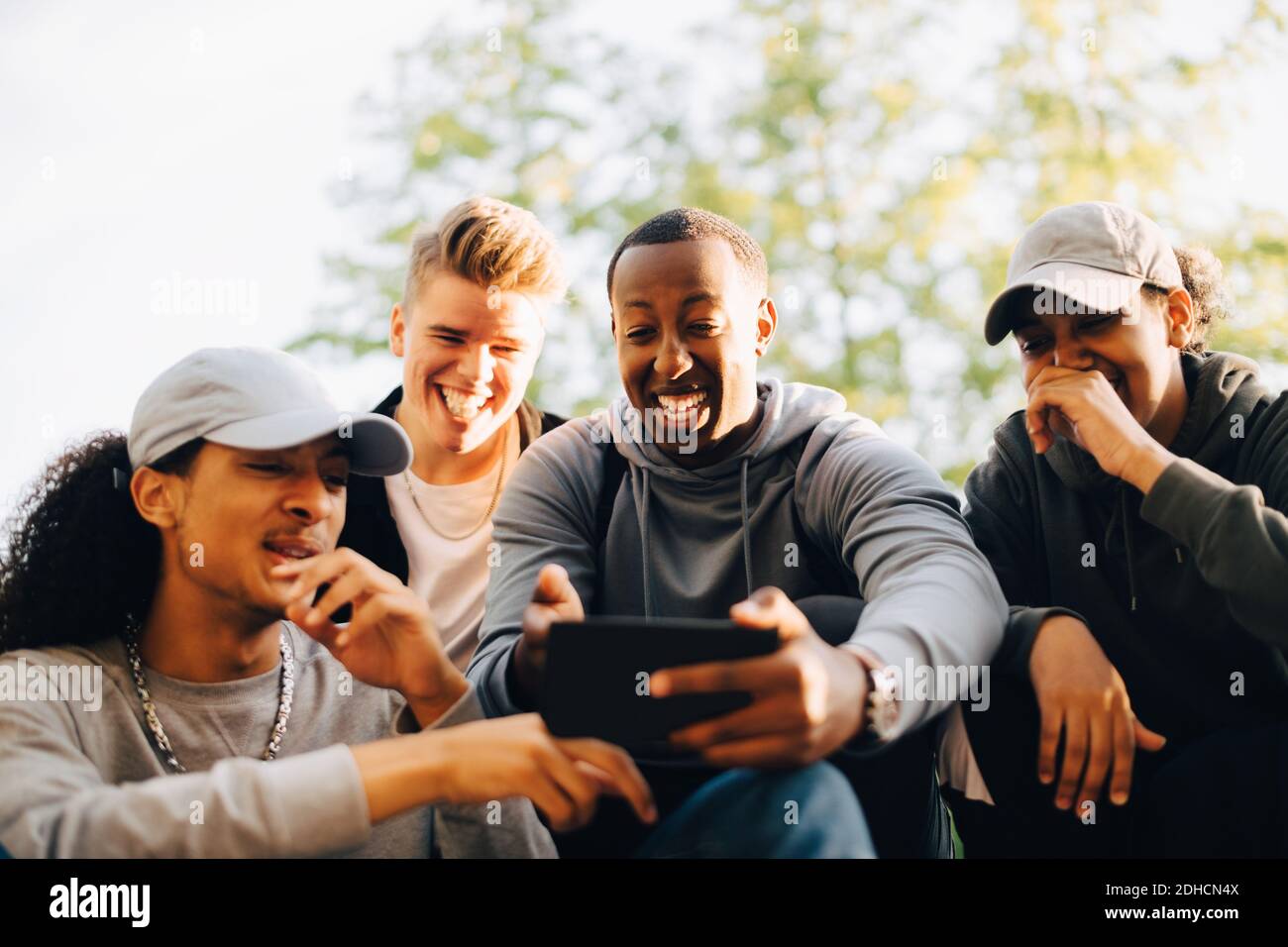 Smiling friends looking at mobile phone in skateboard park Stock Photo