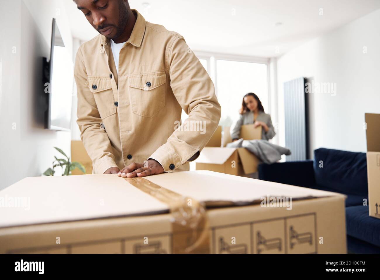 Young couple in lounge at home packing removal boxes ready for house move Stock Photo