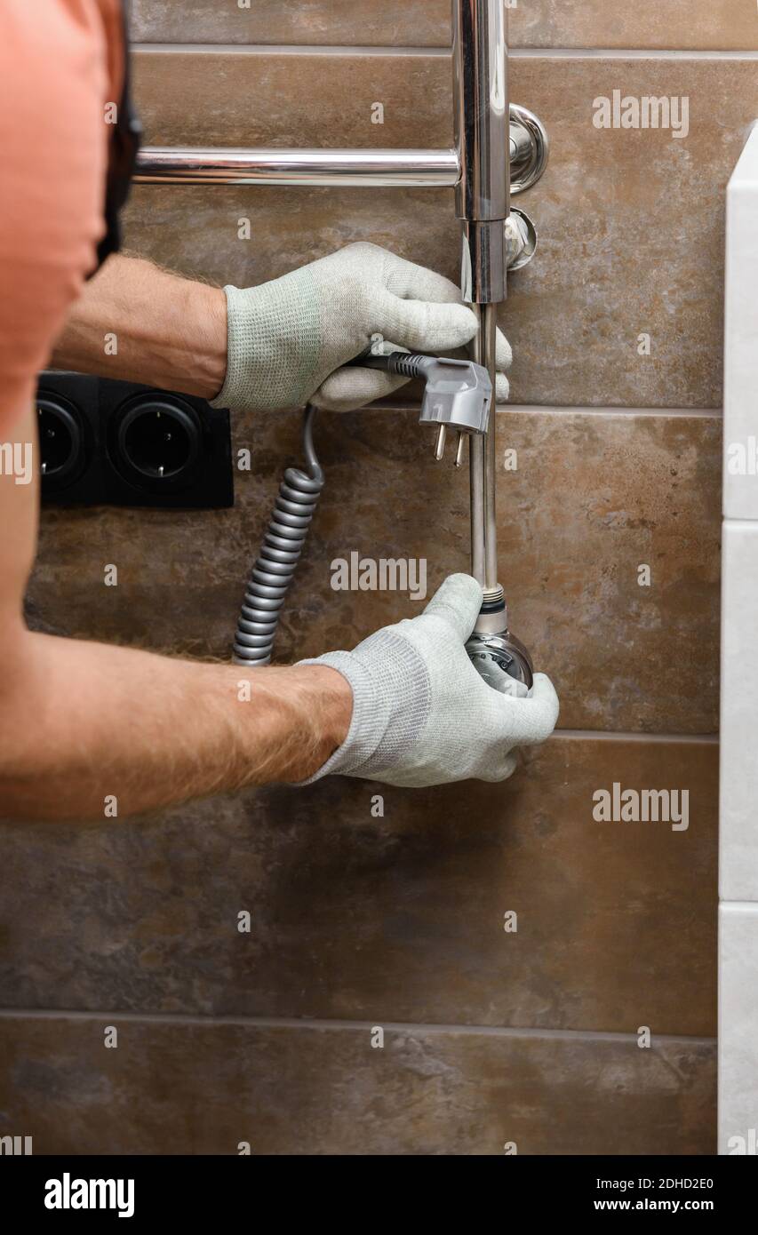 A worker is installing a heating element in the towel warmer in the