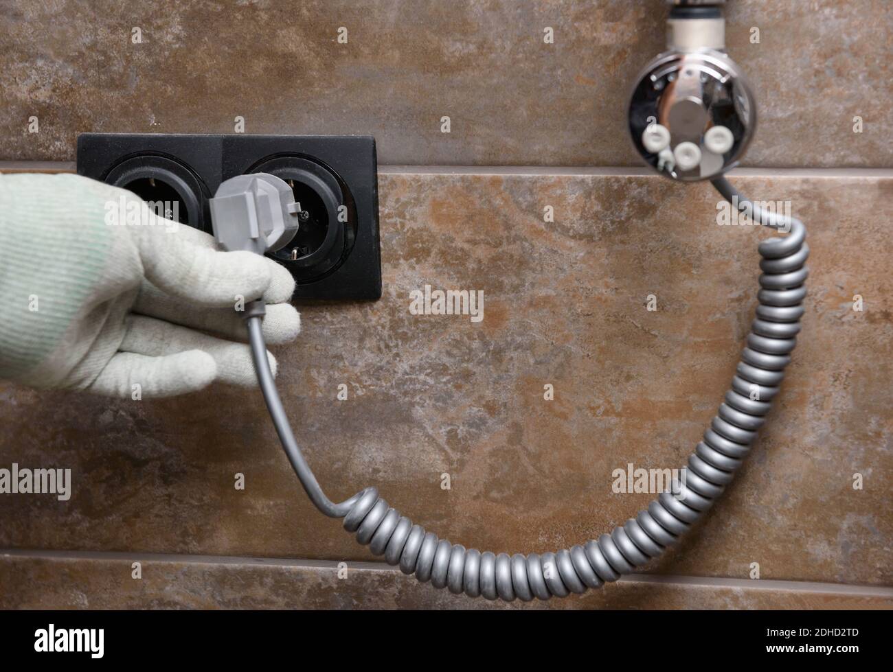 A worker is installing a heating element in the towel warmer in the