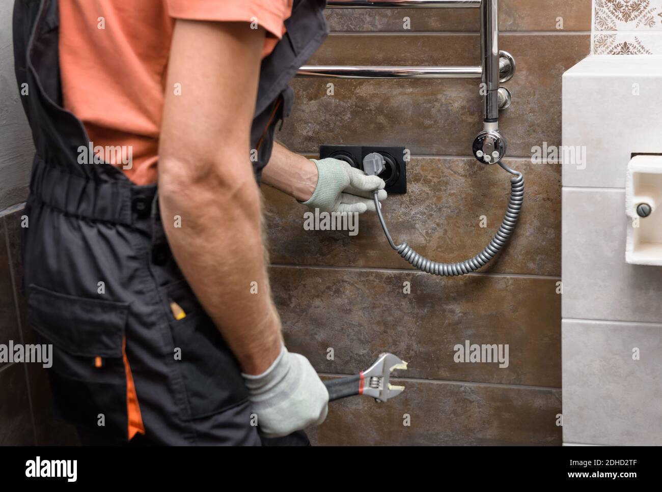 A worker is installing a heating element in the towel warmer in the