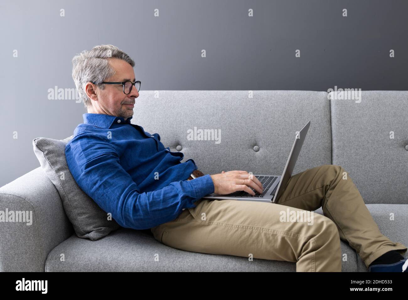 Man Using Laptop Sitting On Couch At Home Stock Photo