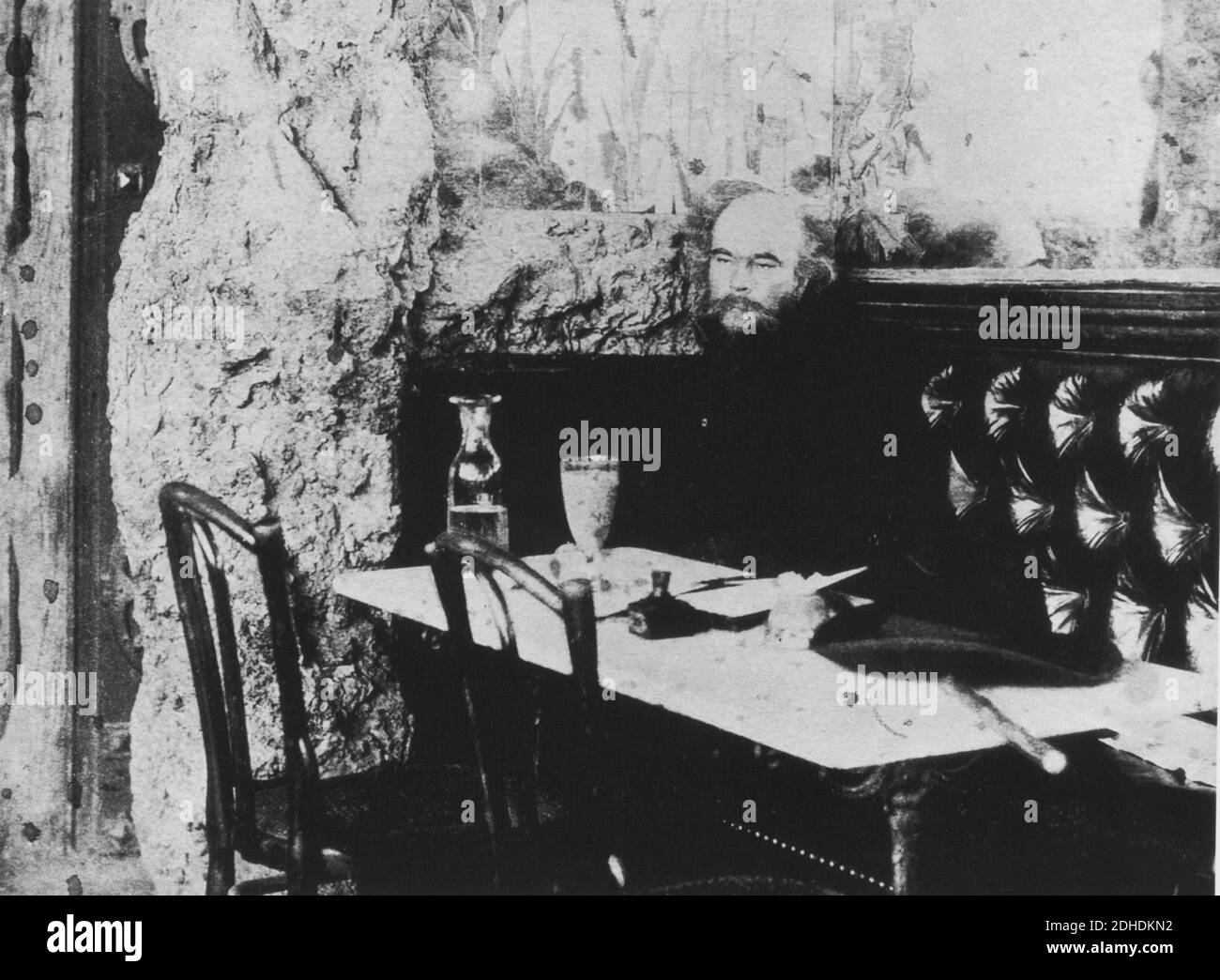 The french poet PAUL  VERLAINE (  1844 -   1896 ) in an absinthe stupor in the Café Procope , Paris . Beside the inkwell stands a glass of his ' humble ephemeral absinthe ' - ASSENZIO - ubriaco - drunk  - POETA - POESIA - POETRY - LETTERATO - LETTERATURA - LITERATURE - Arthur RIMBAUD - gay - homosexual - homosexuality - omosessuale - omosessualità - stempiato - stempiatura - timming at temple  - barba - beard - portrait - ritratto  - SIMBOLISMO - SIMBOLISM - Boheme  - bohemien - bar - caffè - café  ----  Archivio GBB Stock Photo