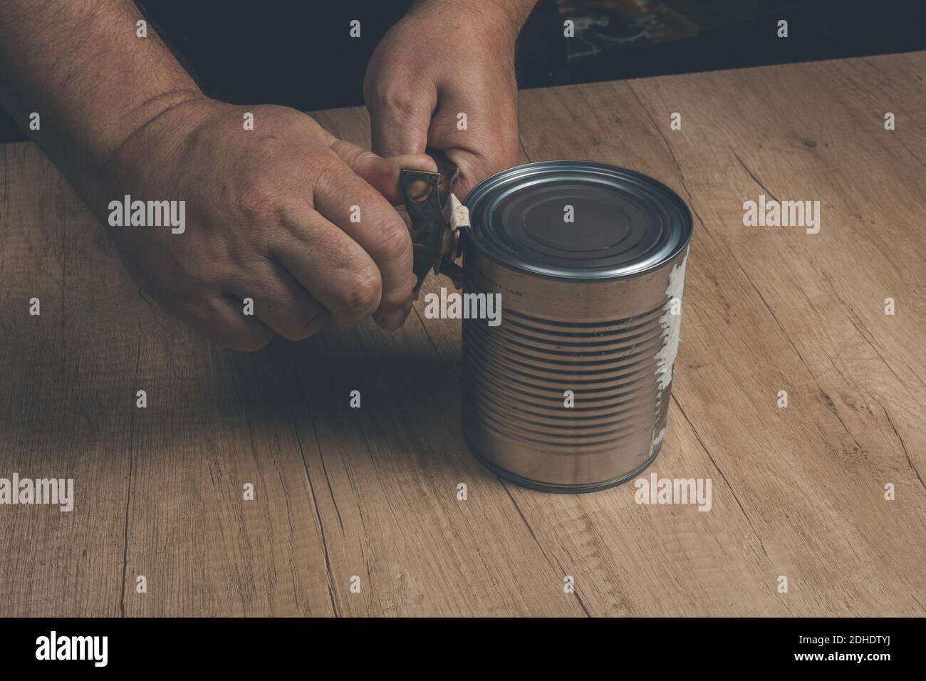 Opening tin can isolated on wooden background. Vintage editing. Concept home working, cooking Stock Photo