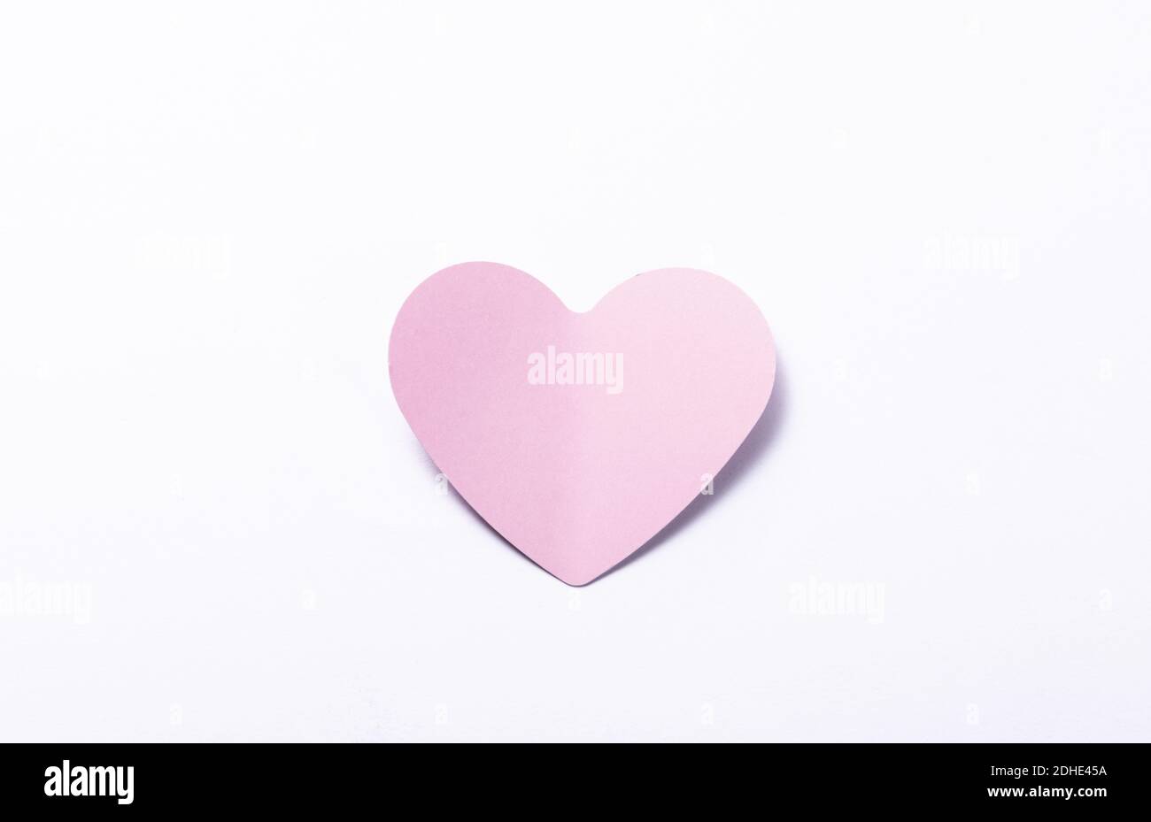 A pink paper heart on the white backgro, the concept of romance, love ...