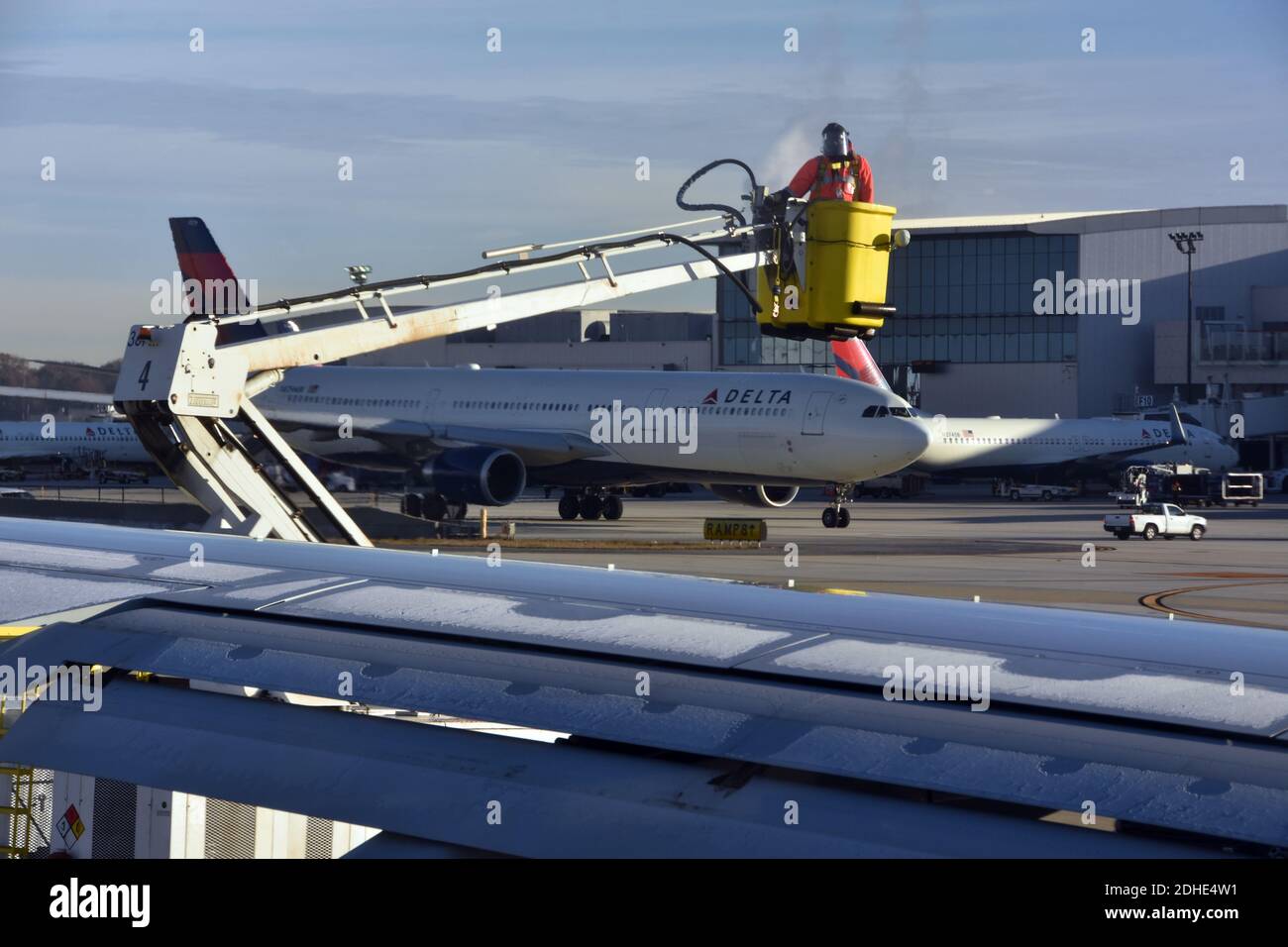 De-Icing airplane at Atlanta airport in winter. Delta airplane in the background. Stock Photo