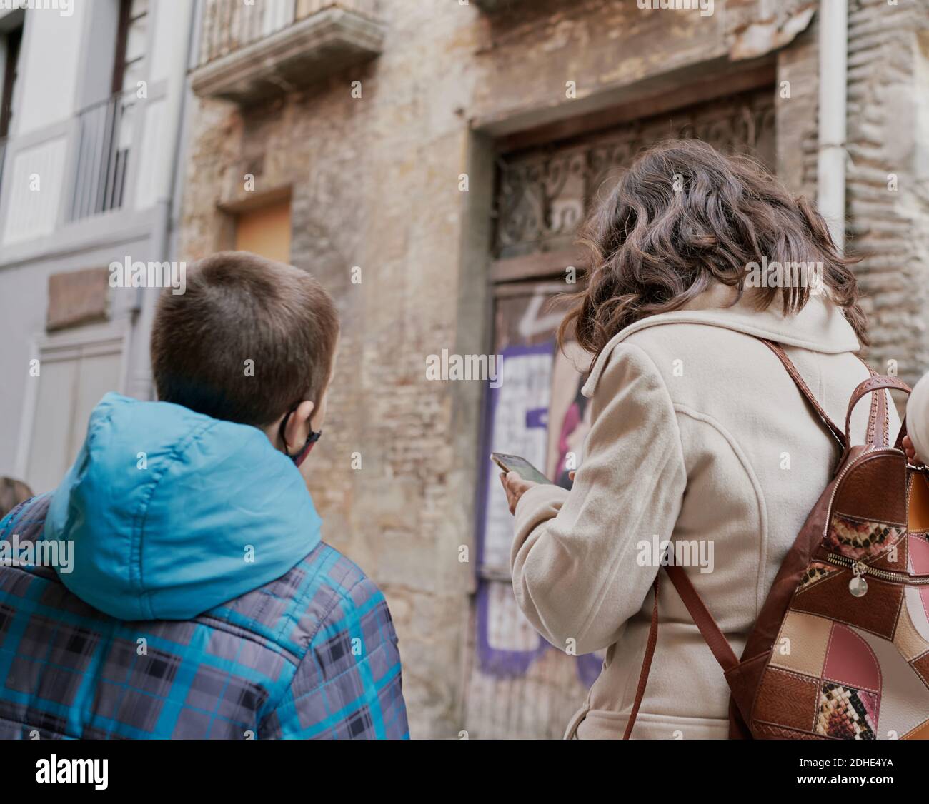 Rear view of mother and son looking at their smartphone wearing winter clothes on the street. vacation concept Stock Photo