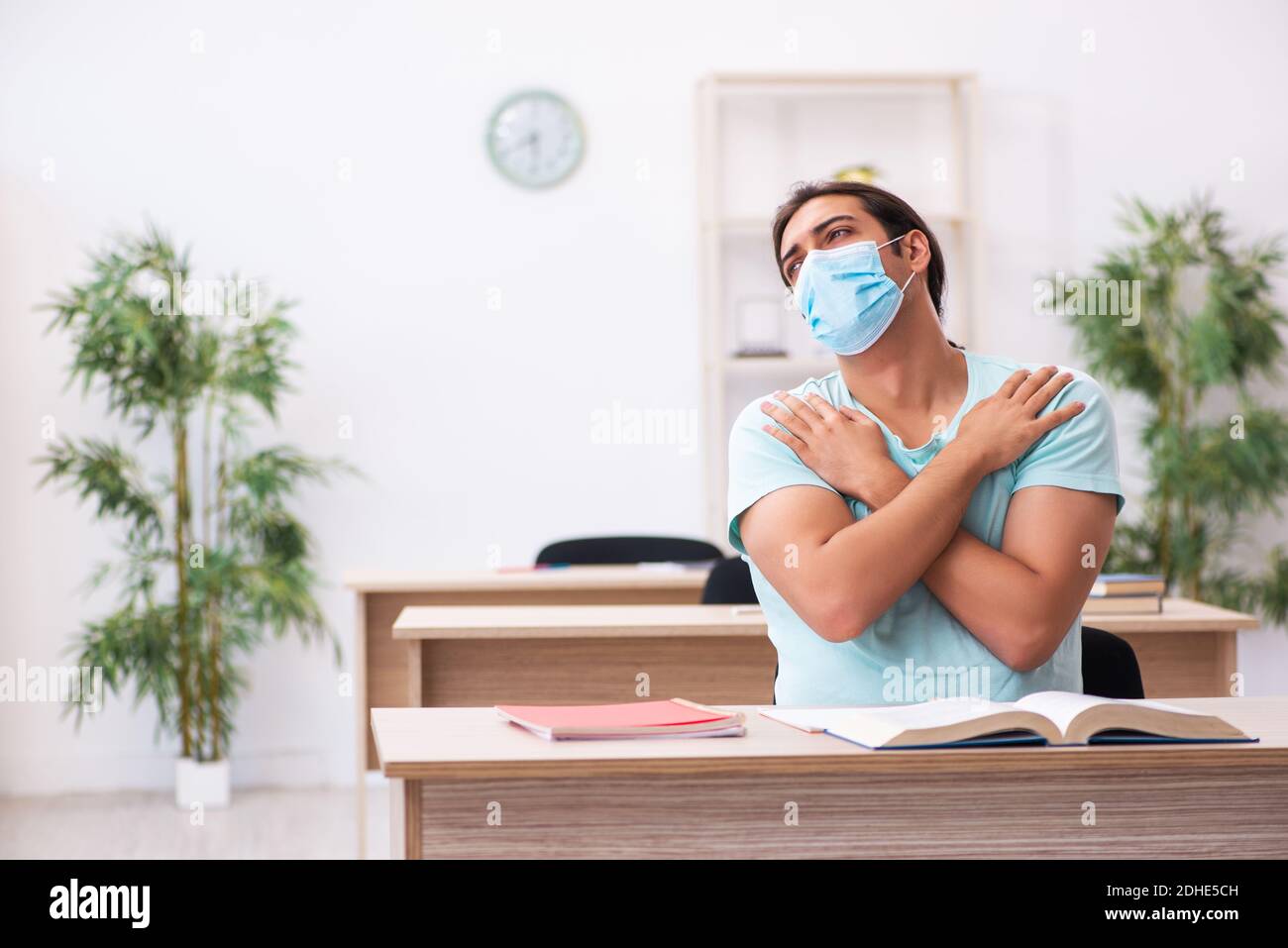 Young male student sitting in the classroom wearing mask Stock Photo ...