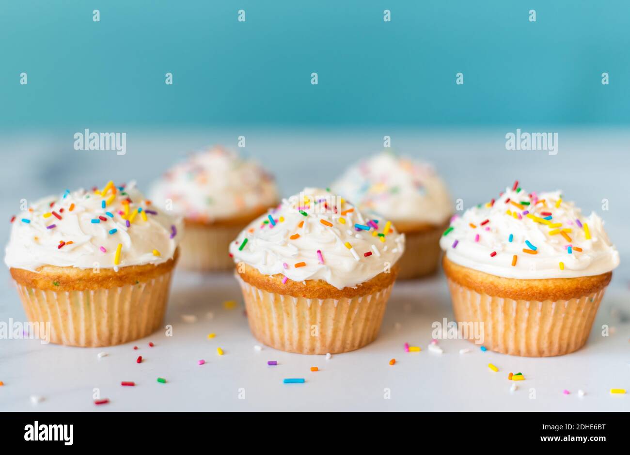 Cupcakes with sprinkles on white table with blue background. Stock Photo