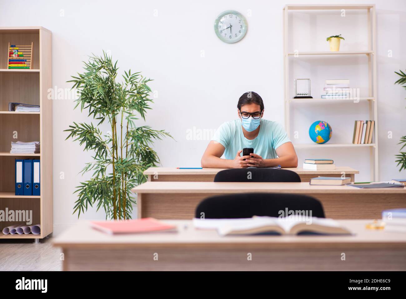 Young male student sitting in the classroom wearing mask Stock Photo ...