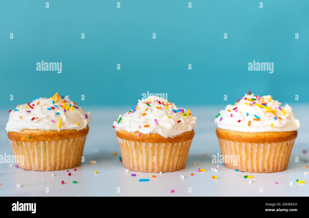 Cupcakes with sprinkles on white table with blue background. Stock Photo