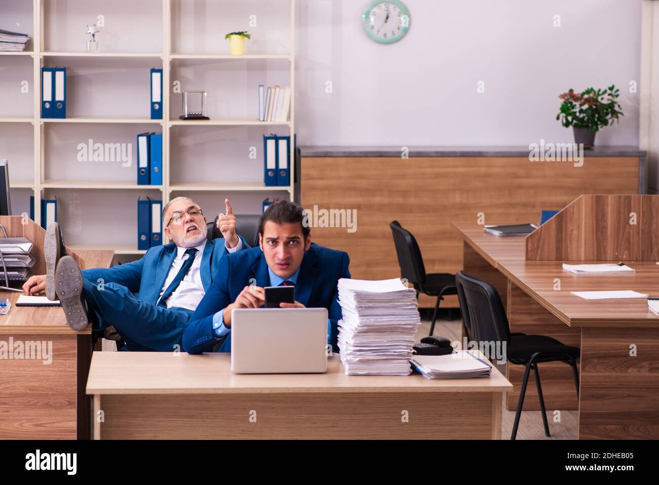 Old male boss and his young male assistant in bullying concept Stock Photo