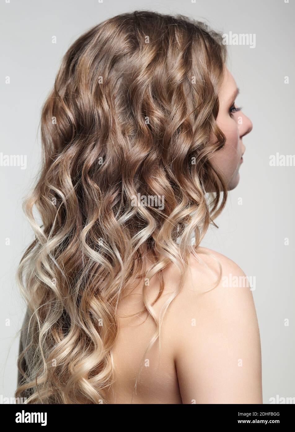 Woman from backside on gray background. Female with curly hair Stock Photo