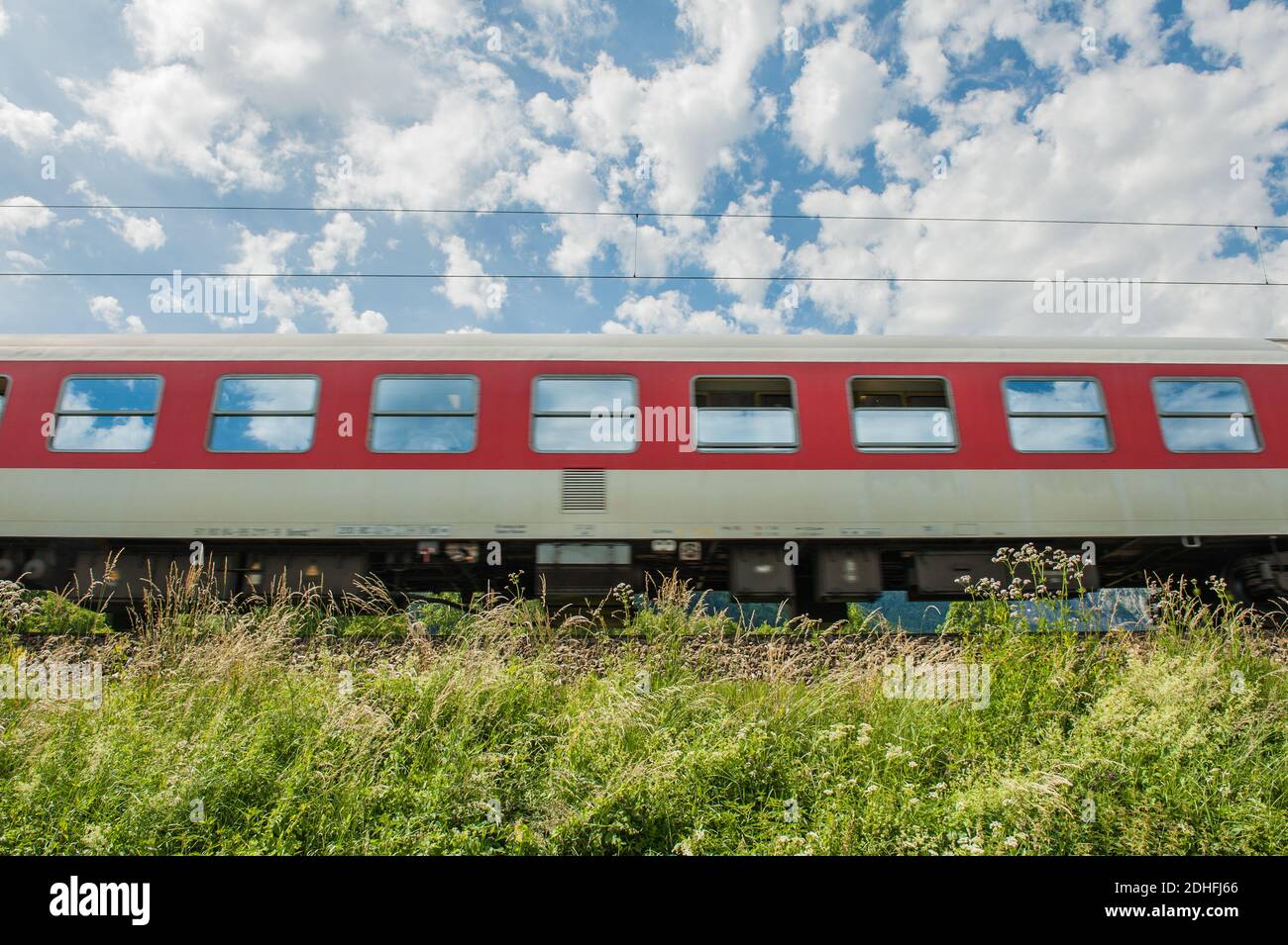 a Train with green Grass in foreground and Cloudy Sky Stock Photo