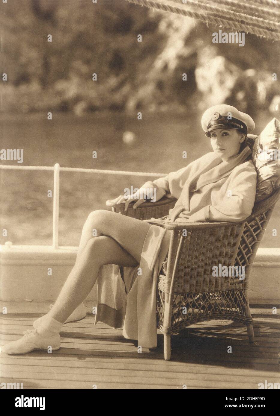 1929 , USA :  GRETA  GARBO at Catalina Island, California ,   in  THE SINGLE STANDARD  (  La  donna che ama  ) by John S. Robertson  , from the romance by Adela Rogers St. Johns  , costume dress by ADRIAN  - MGM - Metro Goldwyn Mayer -  MOVIE - HOLLYWOOD - CINEMA - FILM - actress - attrice  - accappatoio - bath-robe - bathrobe - bath robe - vimini chair - poltrona - cappello da marinaio - navy hat - leggy pose - gambe - yacht - barca - nave - marinaio - sailor - scarpe da tennis ginnastica - white dress - abito vestito bianco casual     ----   Archivio GBB Stock Photo