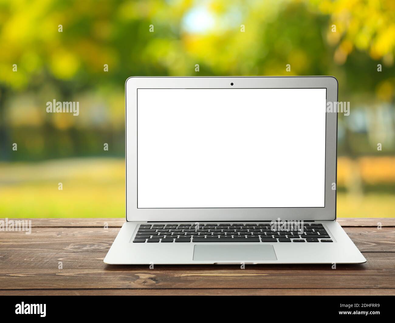 Laptop with blank screen on wooden table outdoors Stock Photo - Alamy