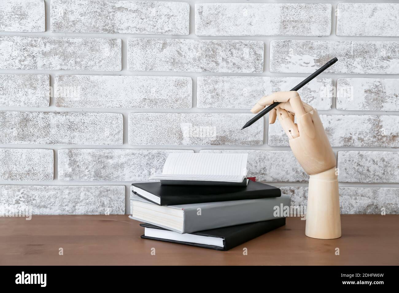 Wooden hand with pencil and notebooks on table Stock Photo - Alamy