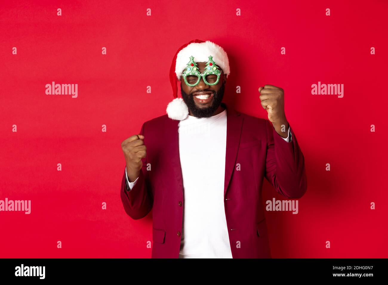 Merry Christmas. Cheerful Black man wearing funny party glasses and santa hat, smiling joyful, celebrating winter holidays, stan Stock Photo