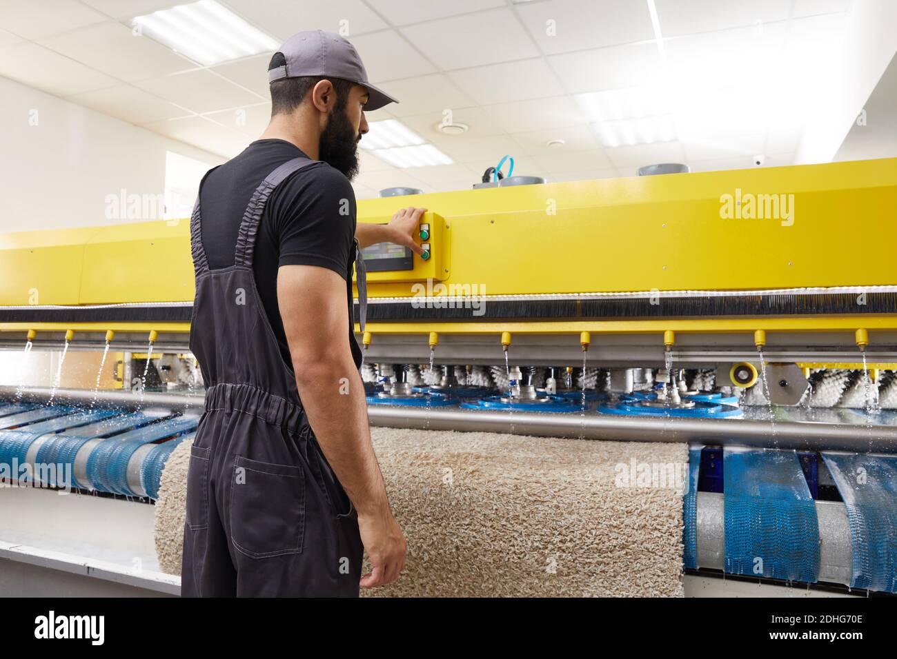 Man operating carpet automatic washing machine in professional laundry service Stock Photo