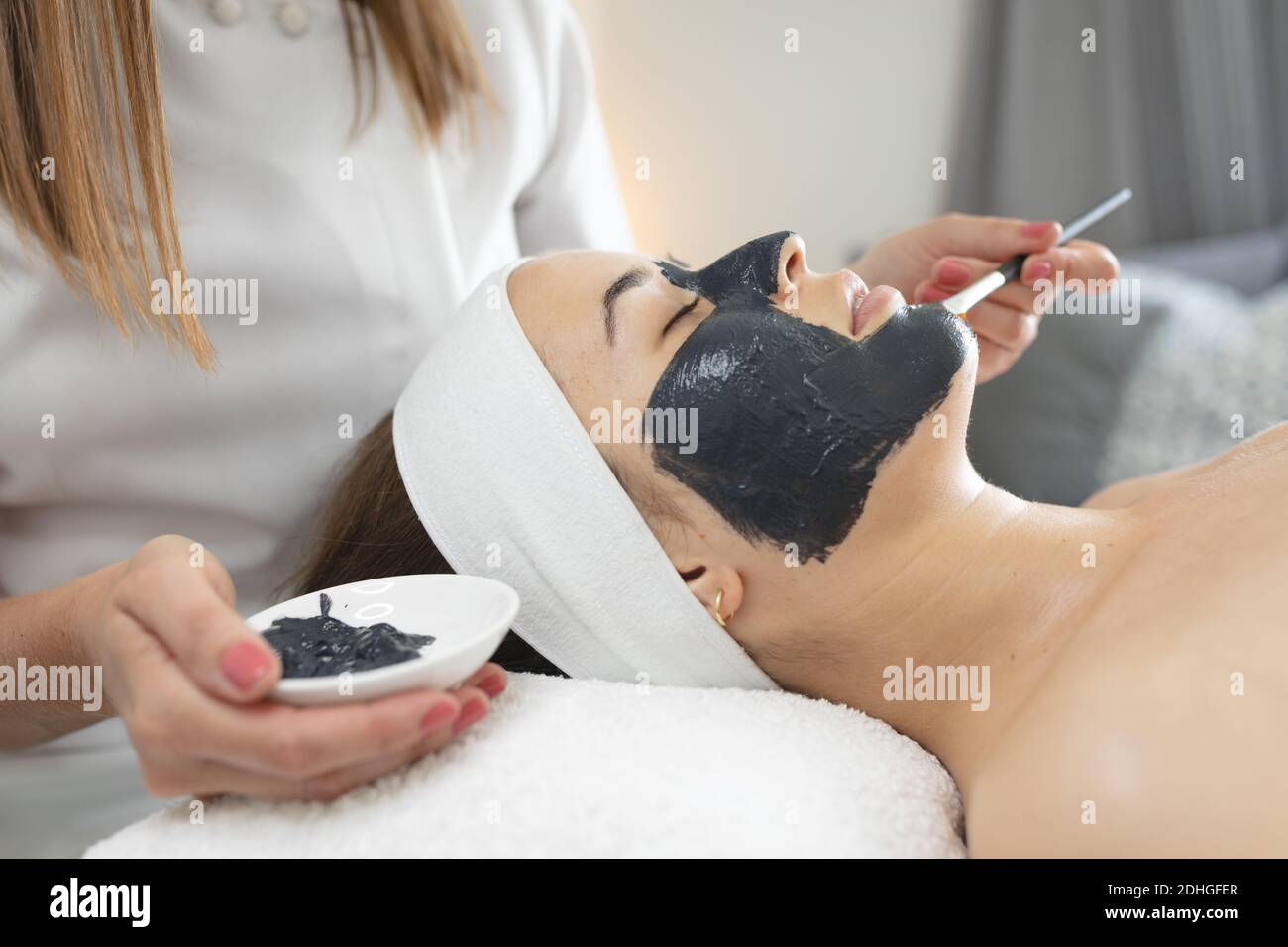 Caucasian Woman Lying Back While Beautician Applies A Face Mask Stock