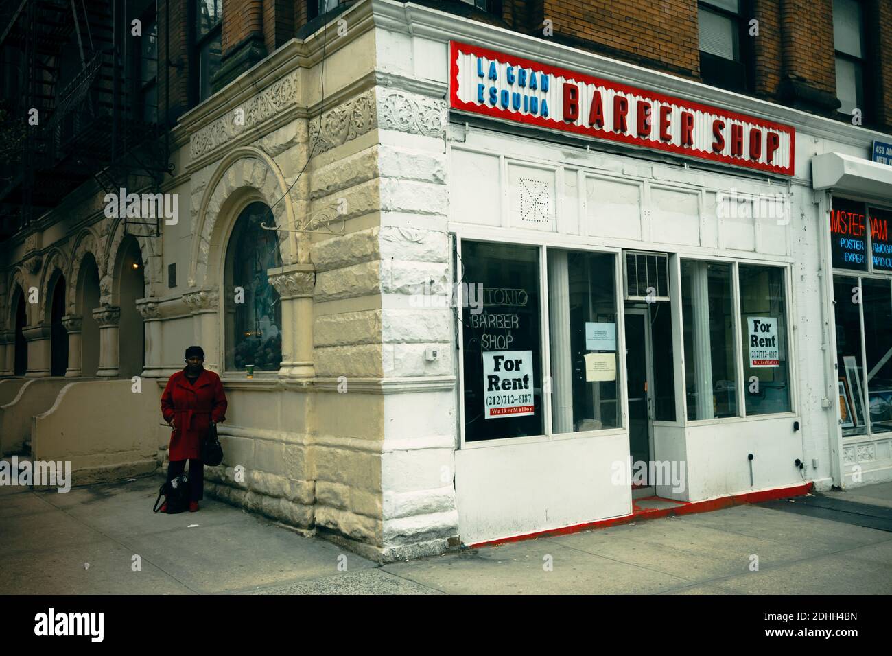 An African American female stands on the sidewalk next to a closed down