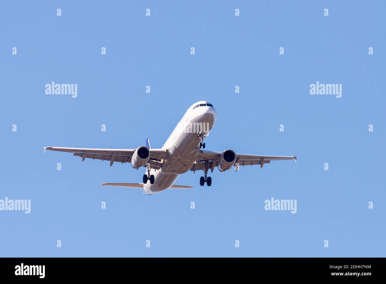 A white airplane flying in a clear pale blue sky Stock Photo - Alamy