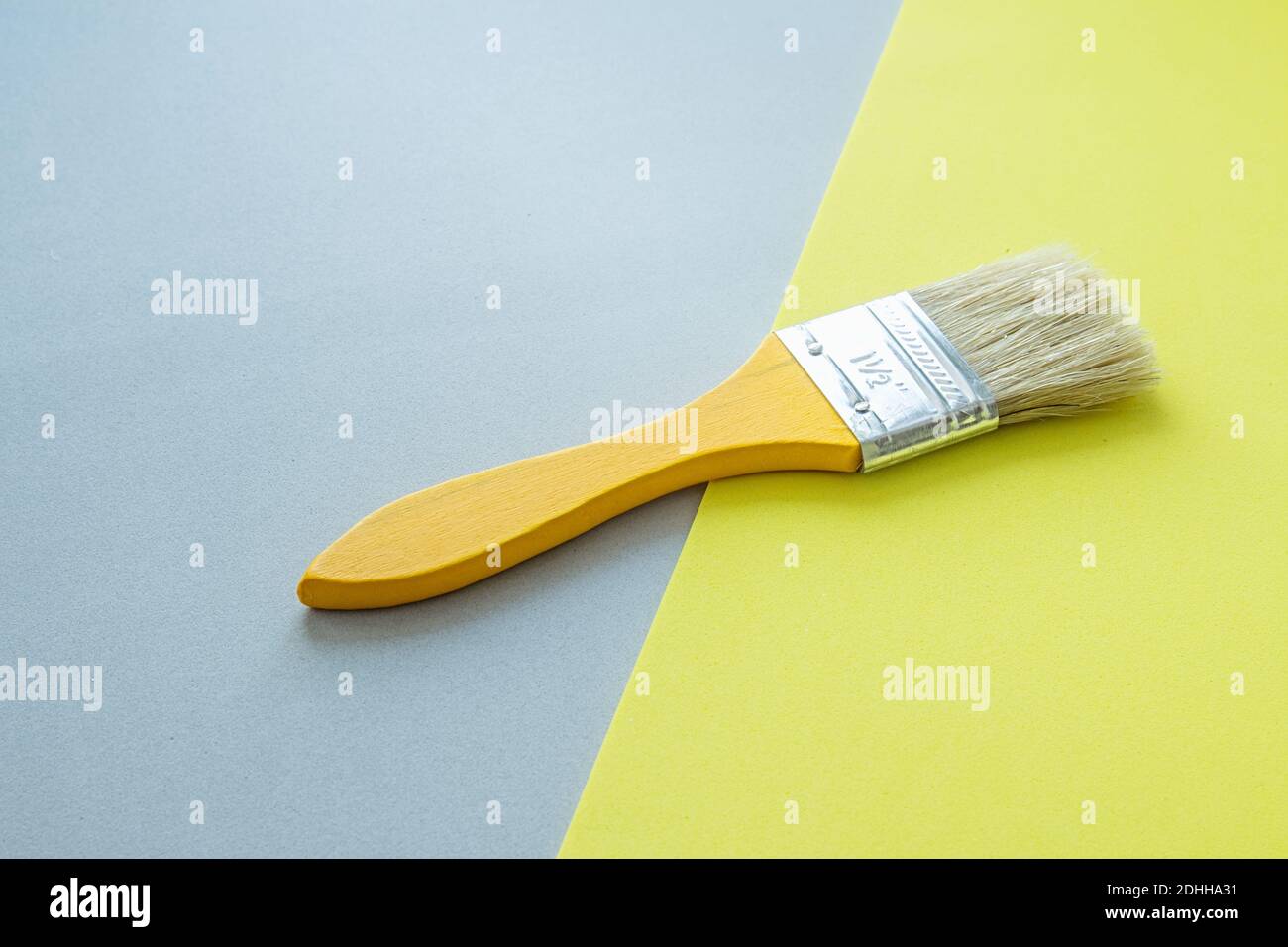 Yellow paint brush on yellow and gray background. Trending color of the year. Home remodeling and renovation concept. Stock Photo