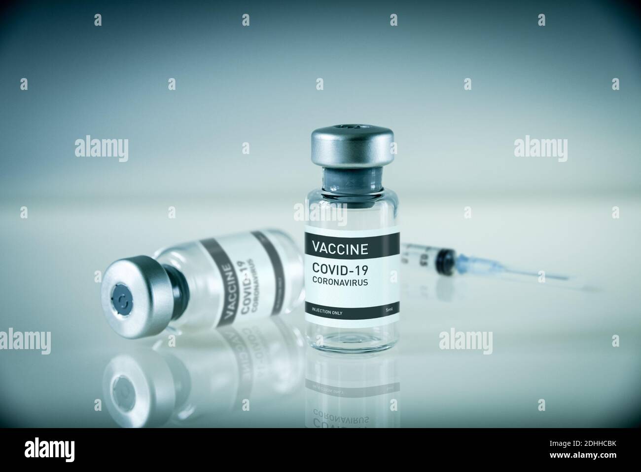 Covid-19 vaccine bottle and syringe on a blue laboratory background ...