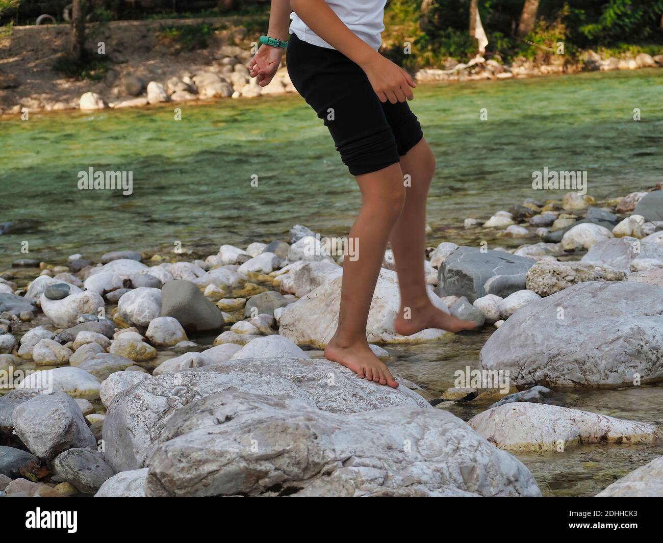 A young male standing on stones in a river Stock Photo - Alamy