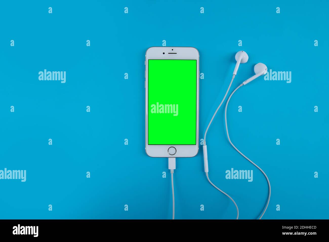 Mobile phone headphones on the blue background . Green screen Stock