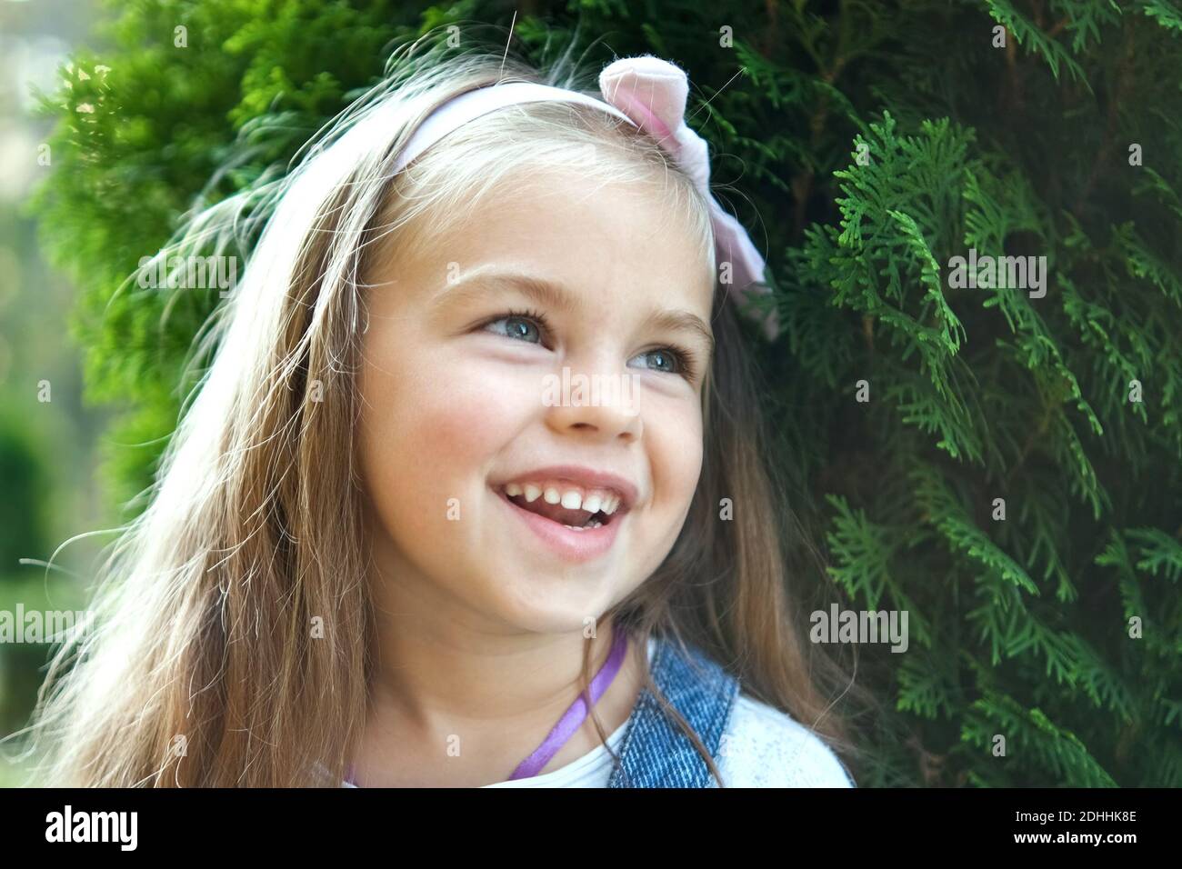 Portrait of pretty child girl standing outdoors in summer park smiling ...
