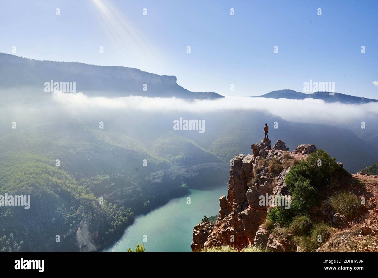 Imagen de un acantilado sobre un rio con niebla al fondo y un hombre observando el paisaje.Tomada en la Comundiad Valenciana Stock Photo