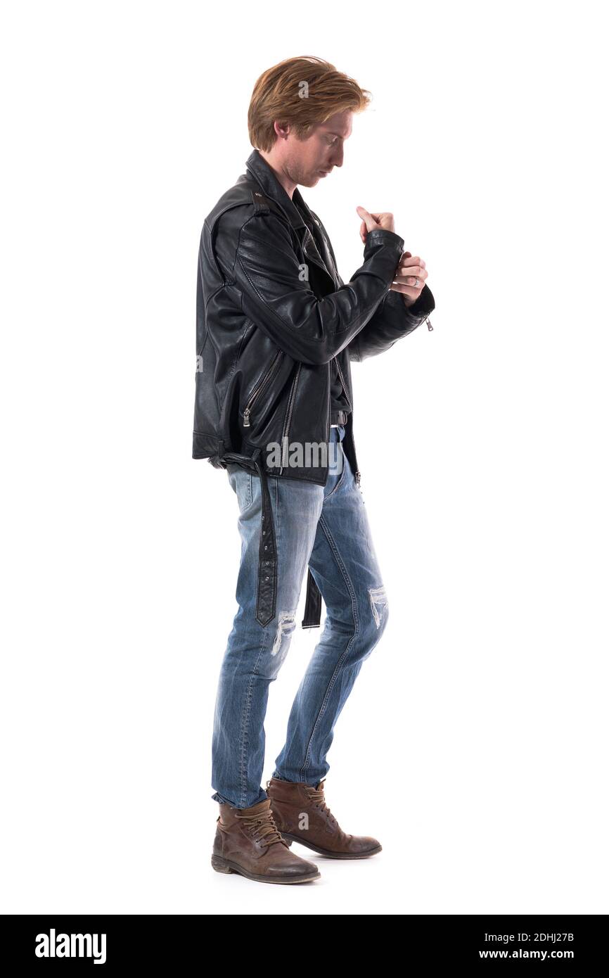 Side view of stylish man in biker style clothes getting dressed buttoning jackets sleeve. Full body length isolated on white background. Stock Photo