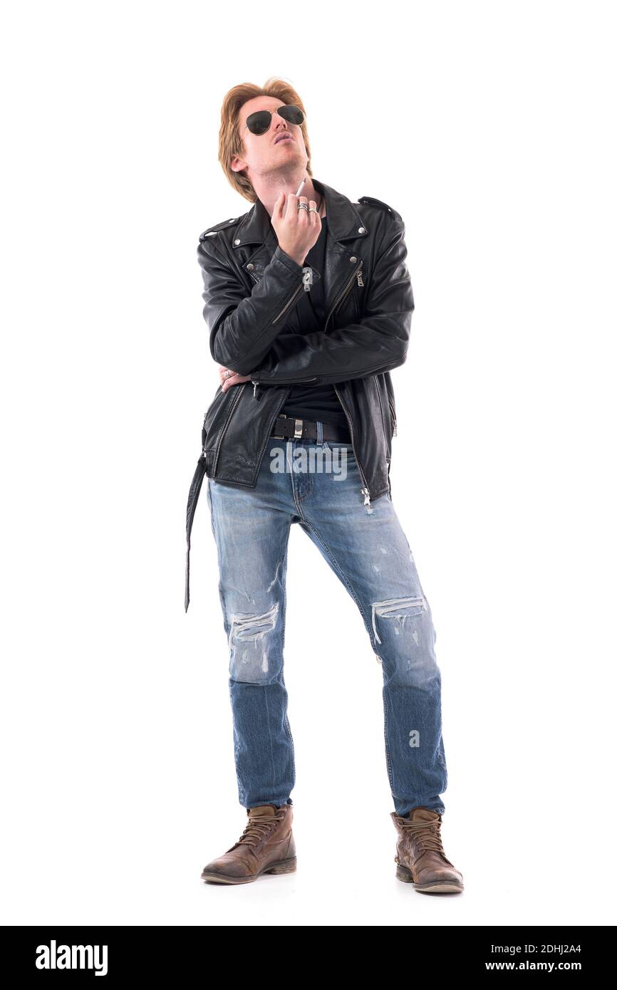 Relaxed cool stylish young man in rocker or bicker style clothes exhale cigarette smoke looking up. Full body length isolated on white background. Stock Photo