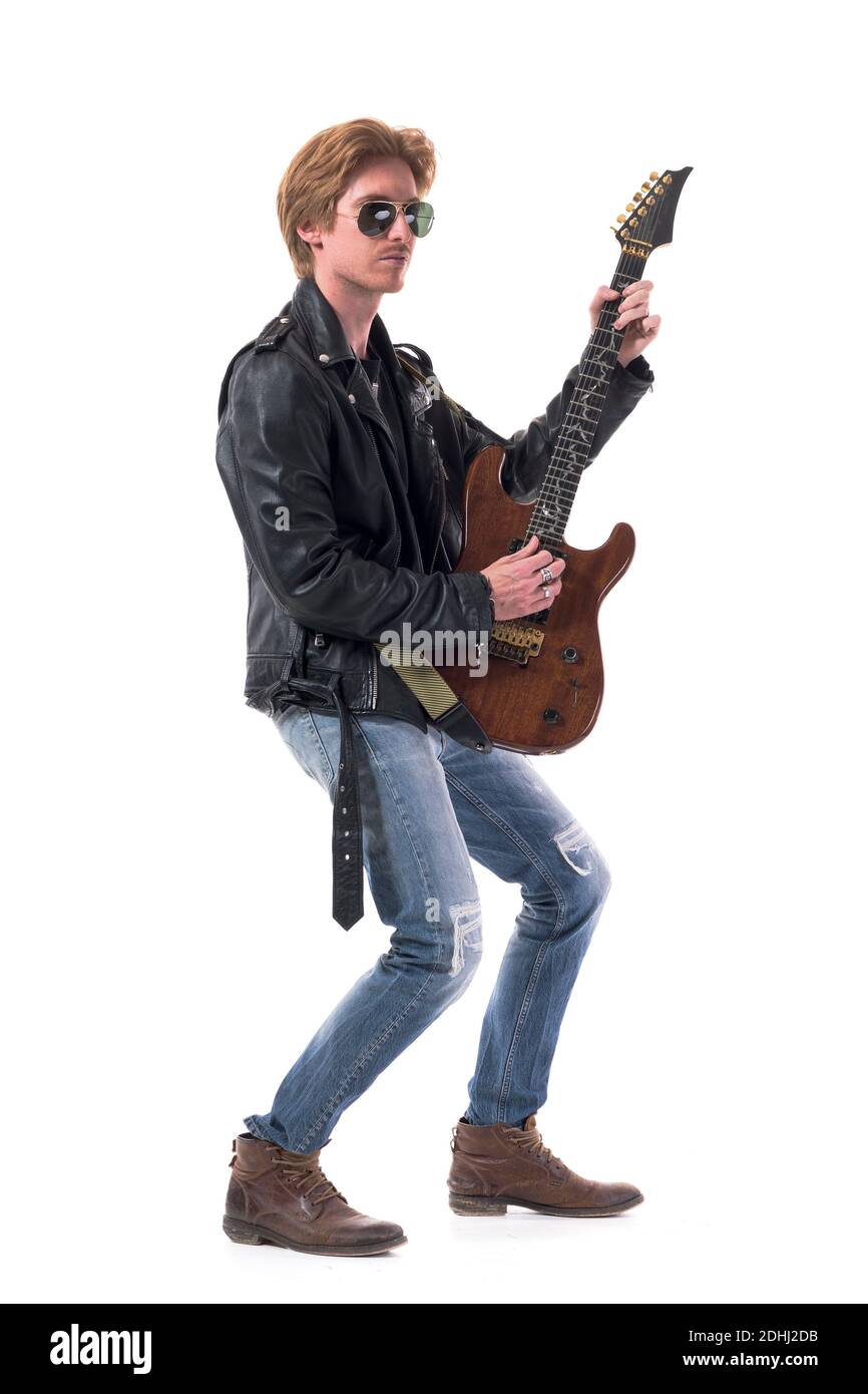 Side view of stylish rocker in leather jacket playing electric guitar wearing sunglasses. Full body length isolated on white background. Stock Photo