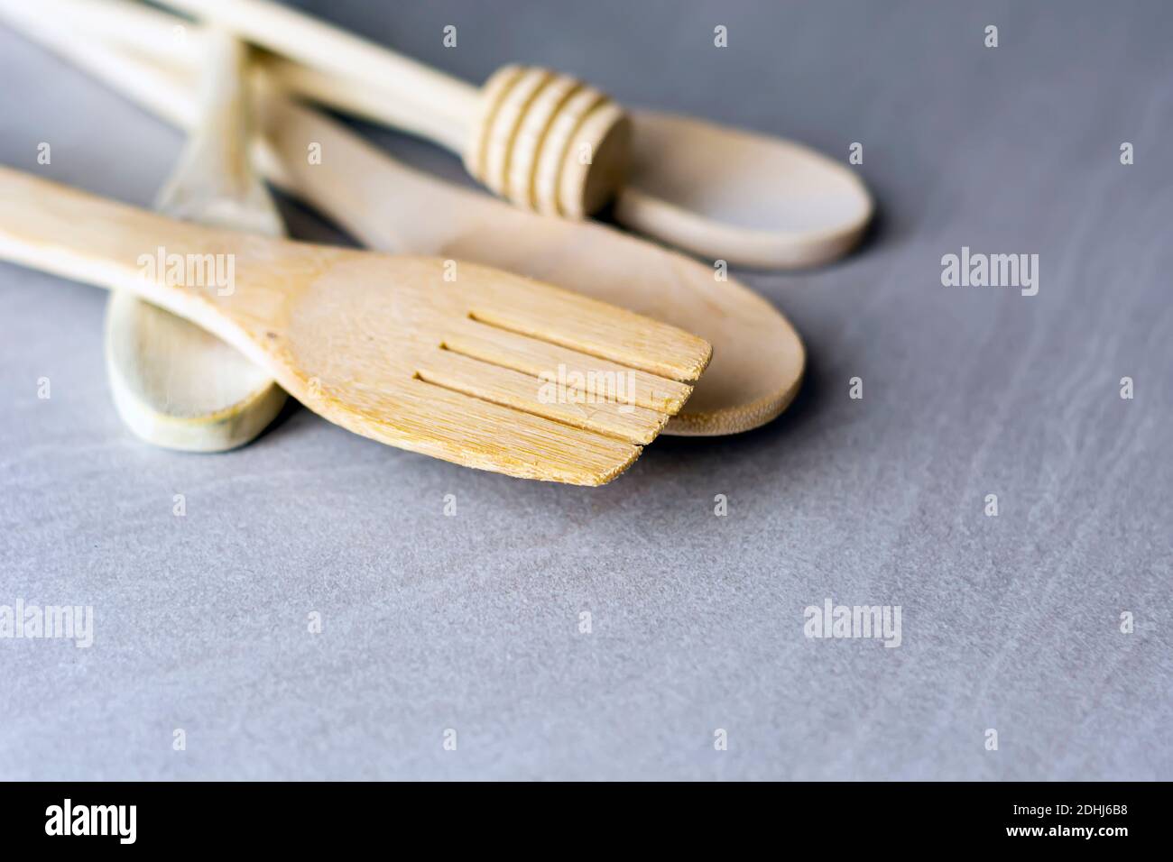 Group of wooden kitchen utensils arranged on a gray marble table. Selective focus on the carving fork. Stock Photo